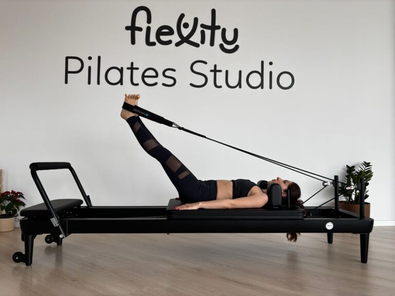 Jurulatih membimbing pelanggan melakukan regangan pilates di studio